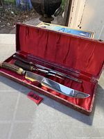 Open case showing knife, fork, steel inside red satin lining