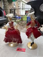 Back view of both Murano dancer figurines showing red glass bodies, gold flecks, bases, hats