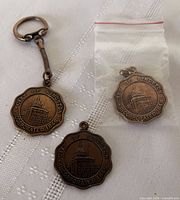 Overview of three medallions, two with keychains, one loose