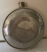 Front view of round pressed aluminum canteen showing screw cap and surface wear