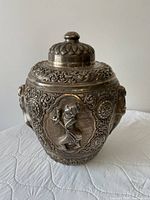 Front view of silver tea caddy showing repoussé figure and scrollwork