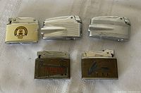 Front view of all five lighters showing graphics, chrome finishes and commemorative details