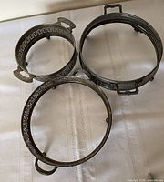 Top view of all three round silver-plated holders showing pierced walls, handles and feet