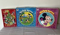 Group shot of three Whitman Disney round jigsaw puzzle boxes