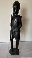 Full frontal view of ebony warrior statue holding spear