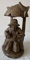 Front view of carved wood figurine showing man, basket, roof