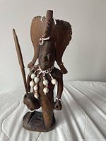 Front view of carved Maasai warrior statue with beadwork and accessories