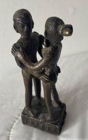 Front view of bronze embrace sculpture on plinth