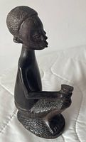 Front-left view of carved ebony crouching man figurine showing vessel and facial details