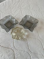 Top view of two smoke-grey square ashtrays and one clear round ashtray