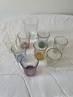 Group of nine coloured and clear shot glasses upright