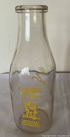 Front view of clear glass bottle with yellow Riverside Dairy graphics
