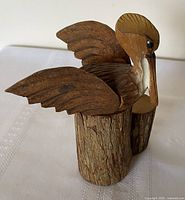 Front angled view showing pelican atop stump, feather and bark details