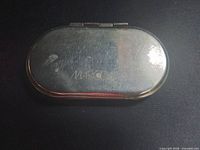 Closed compact top view showing engraved Marc Cain logo and exterior wear