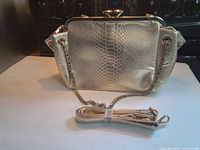 Rear view of metallic gold python-embossed bag showing chain strap and wrapped detachable strap