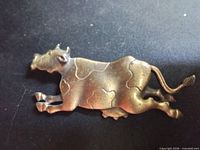 Front view of gold-tone pewter cow brooch
