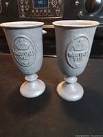 Front view of both pewter goblets showing raised medallion