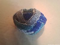 Top view showing interlaced dome knot fully pavé-set with clear, dark blue and teal crystals