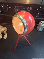 Front angled view showing spherical lamp, chrome ring, tripod legs