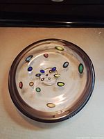 Top view showing clear glass bowl with coloured spots and dark rim