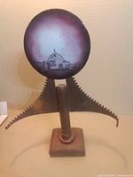 Front view showing full sculpture with painted disc, blade, rod, base