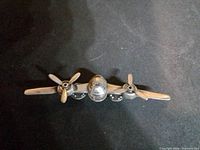 Front view of silver-tone B-25 bomber brooch showing wings, fuselage, propellers