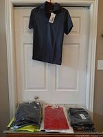 Front view of navy Core 365 polo on hanger above stacked packaged shirts
