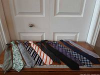 All eleven neckties laid out on table with yardstick for scale