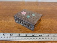 Top view showing floral inlay and overall size reference with ruler