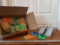 box of neon track pieces, two gray ramps, two LED cars