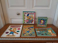 All five Simpsons books standing and lying flat for size reference