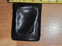 Front view of black leather bi-fold wallet showing overall condition and embossed logo
