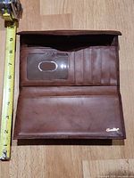 Wallet open showing card slots, ID window, measuring tape for scale