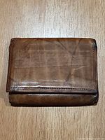 Exterior view of closed wallet showing brown leather surface and wear