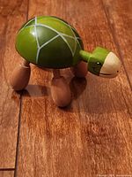 Side view of green wooden turtle figurine on wood floor
