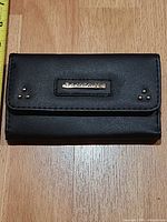 Front view of closed Rampage wallet showing logo plaque and studs