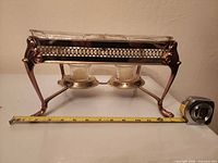 Full side view of chafing stand with glass pans and fuel holders, tape for length