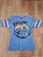 Full front view of gray Superman T-shirt laid flat on floor