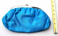Full front view of blue satin clutch with tape measure showing length