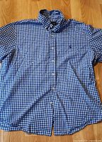 Front view of entire blue and white plaid shirt laid flat