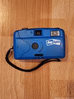 Front view of blue Snap Sights camera showing lens cover, viewfinder, flash and logo