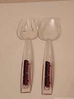 Full view of fork and spoon showing clear acrylic bodies and logos
