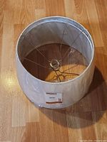 Single white drum lampshade showing spider fitter and plastic wrap