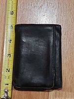 Wallet folded beside tape for scale