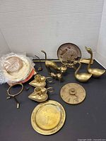 Group shot of all brass items including coasters, animals, lamps, spinner, tray, plate and stand