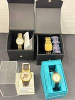 Four boxed/displayed wristwatches showing overall lot