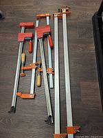 All six bar clamps arrayed on floor showing full lengths and jaws