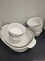 Oval white CorningWare casserole with glass lid; six white fluted ramekins visible