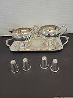 Full lot showing creamer, sugar bowl on tray, four shakers