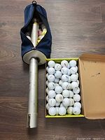 Retriever tube in sleeve next to open box of golf balls